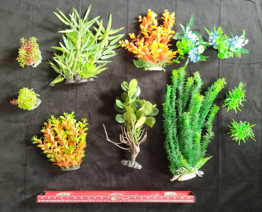 Collection of various artificial plants on a black background with a ruler for scale.