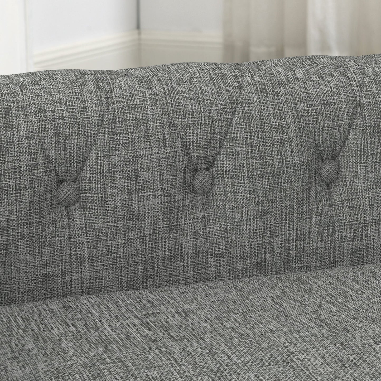 Gray fabric sofa with tufted button details in a room setting.