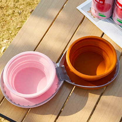 Collapsible pink and orange bowls on a wooden table with a magazine in the background.