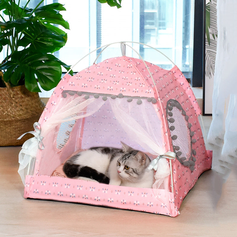 Cat lying inside a pink pet tent with decorative elements on a wooden floor.