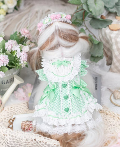 Toy figure in a green dress with floral headband surrounded by flowers and decorative items