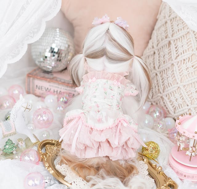 Person with a doll wearing a pink dress surrounded by decorative items