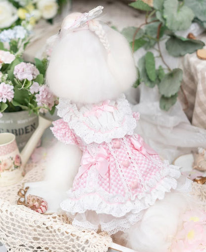 White bird with a pink lace dress in a decorative setting with flowers and lace.