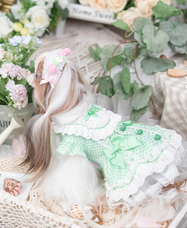 Doll with floral hair accessories and a green dress surrounded by flowers and greenery