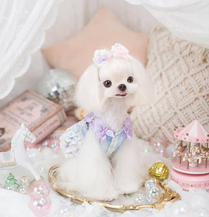 Small white dog wearing a decorative outfit with a pink castle and unicorn toy in the background