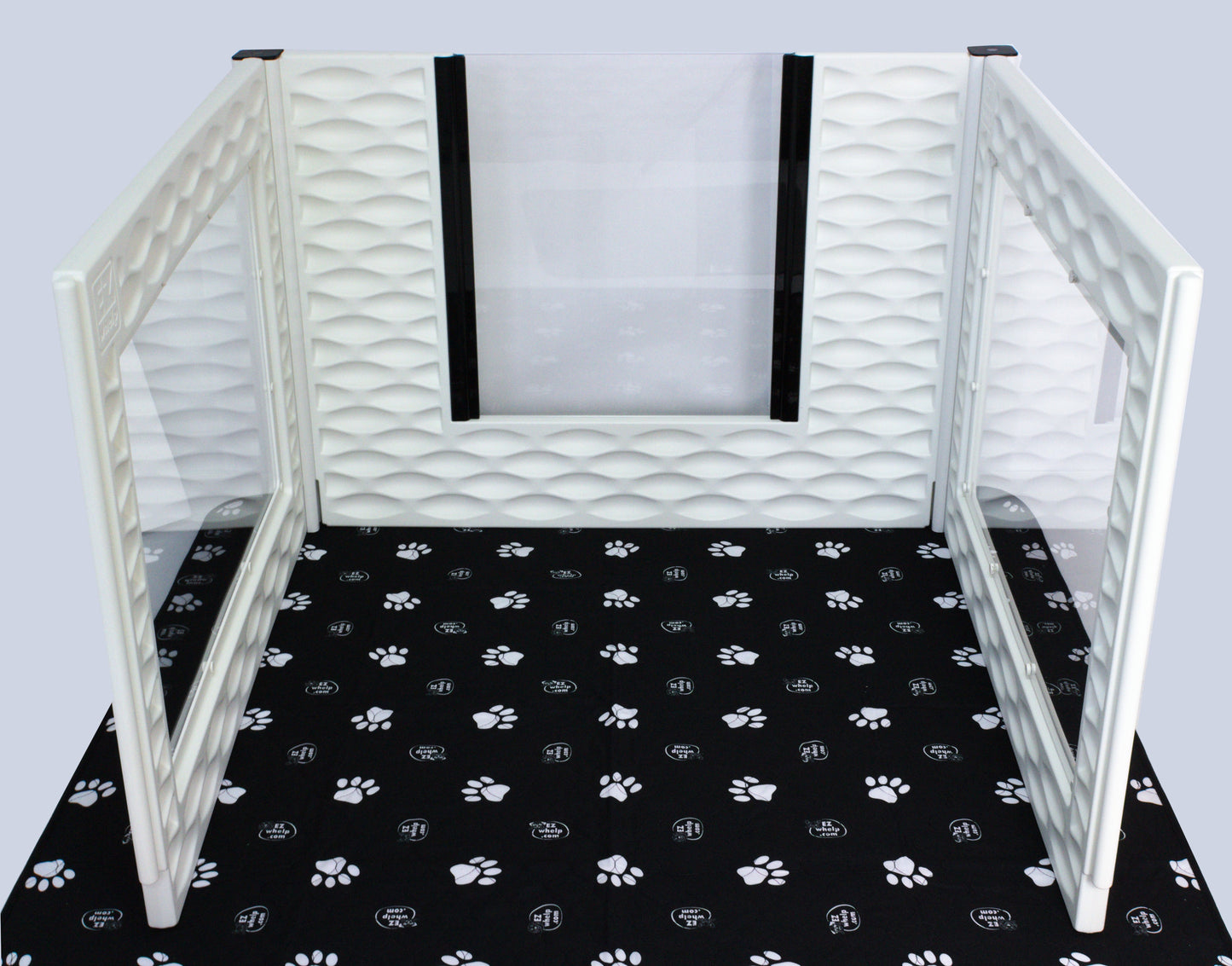 Pet playpen with white mesh walls on a black mat with paw prints