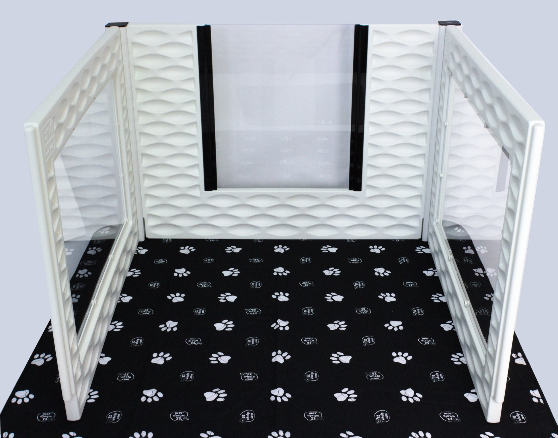 Pet playpen with white mesh walls on a black mat with paw prints