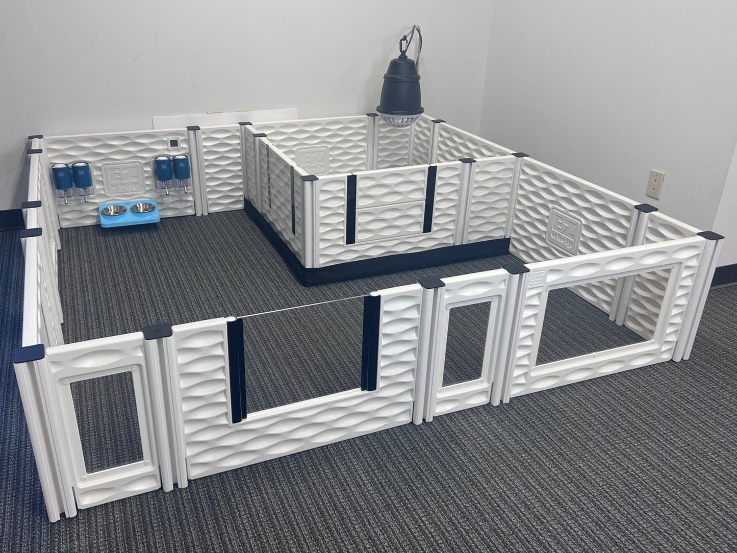 Pet playpen with various toys and accessories on a carpeted floor.