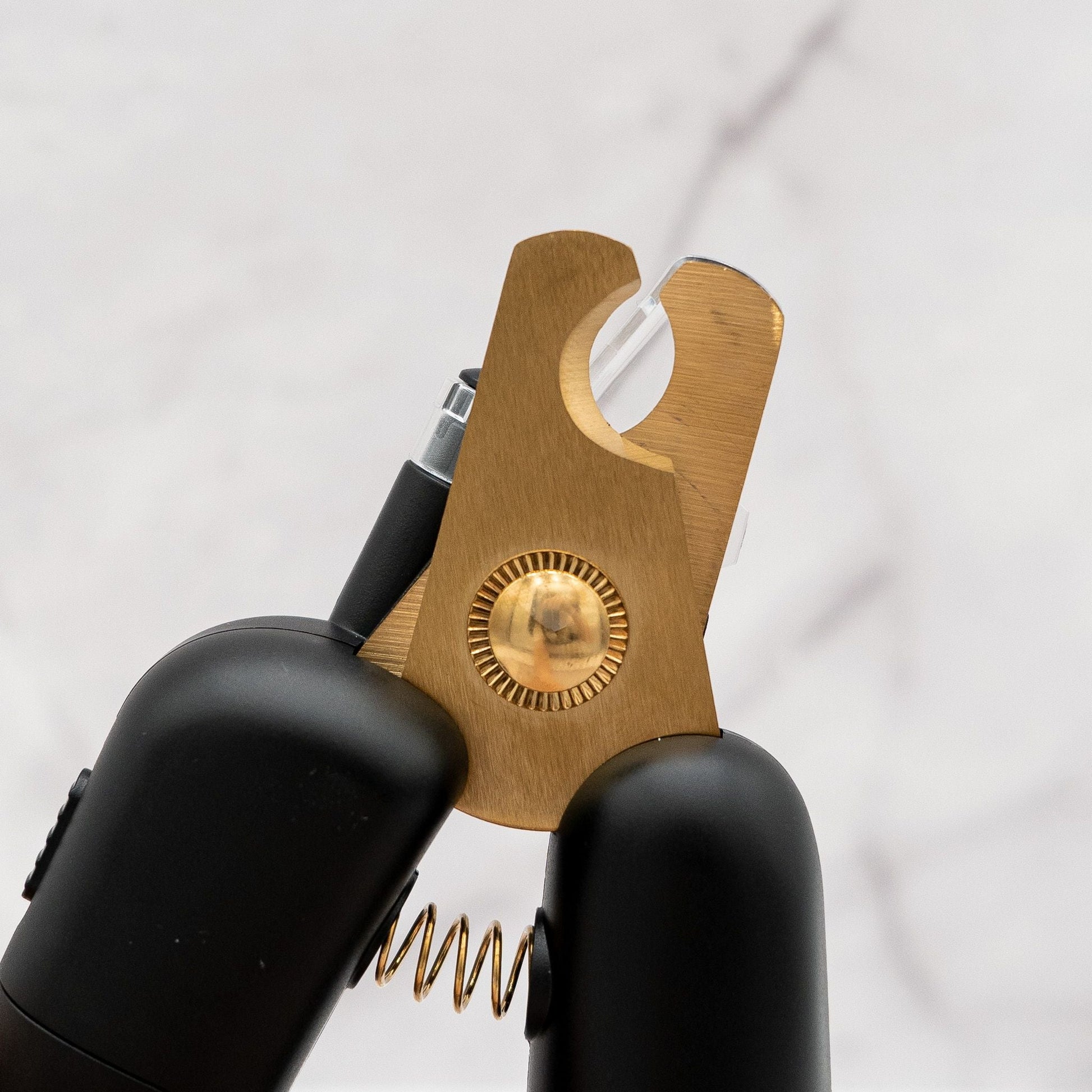 Black and gold tool with a spring mechanism on a white background