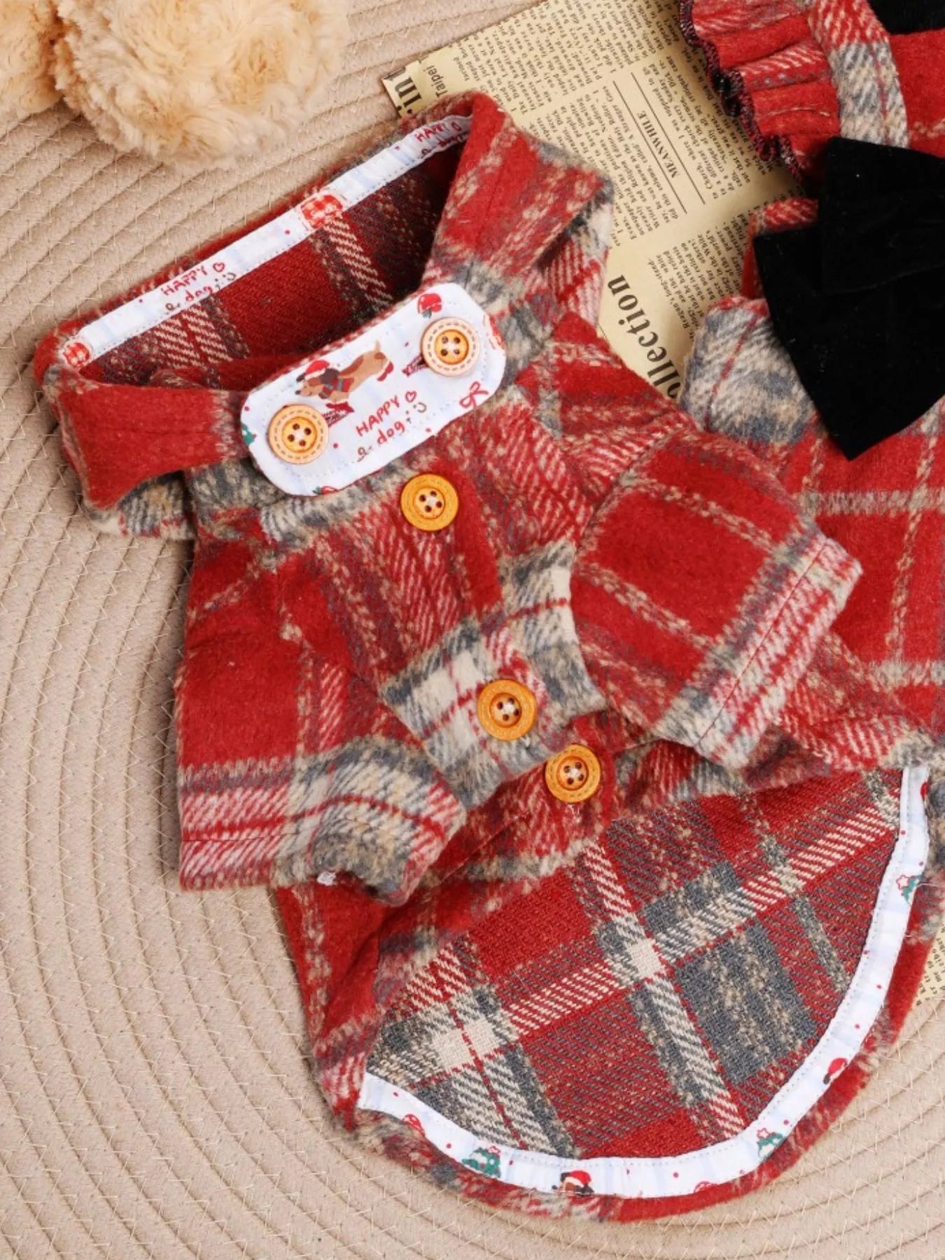 Red plaid dog coat with buttons on a textured surface
