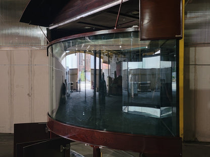 Large curved glass panel with wooden frame in an indoor setting