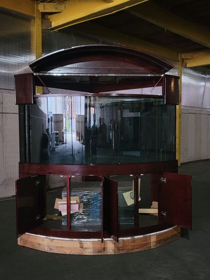 Large curved glass display case with wooden frame in a warehouse setting