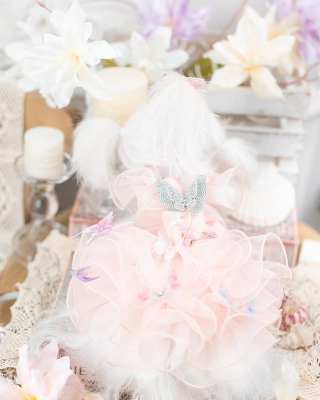 Pastel-colored plush toy with decorative elements on a soft, textured background