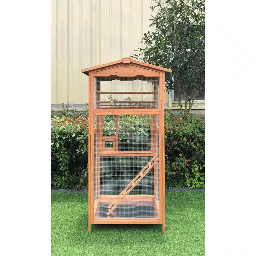 Wooden bird cage with a clear front on a grassy area with plants in the background