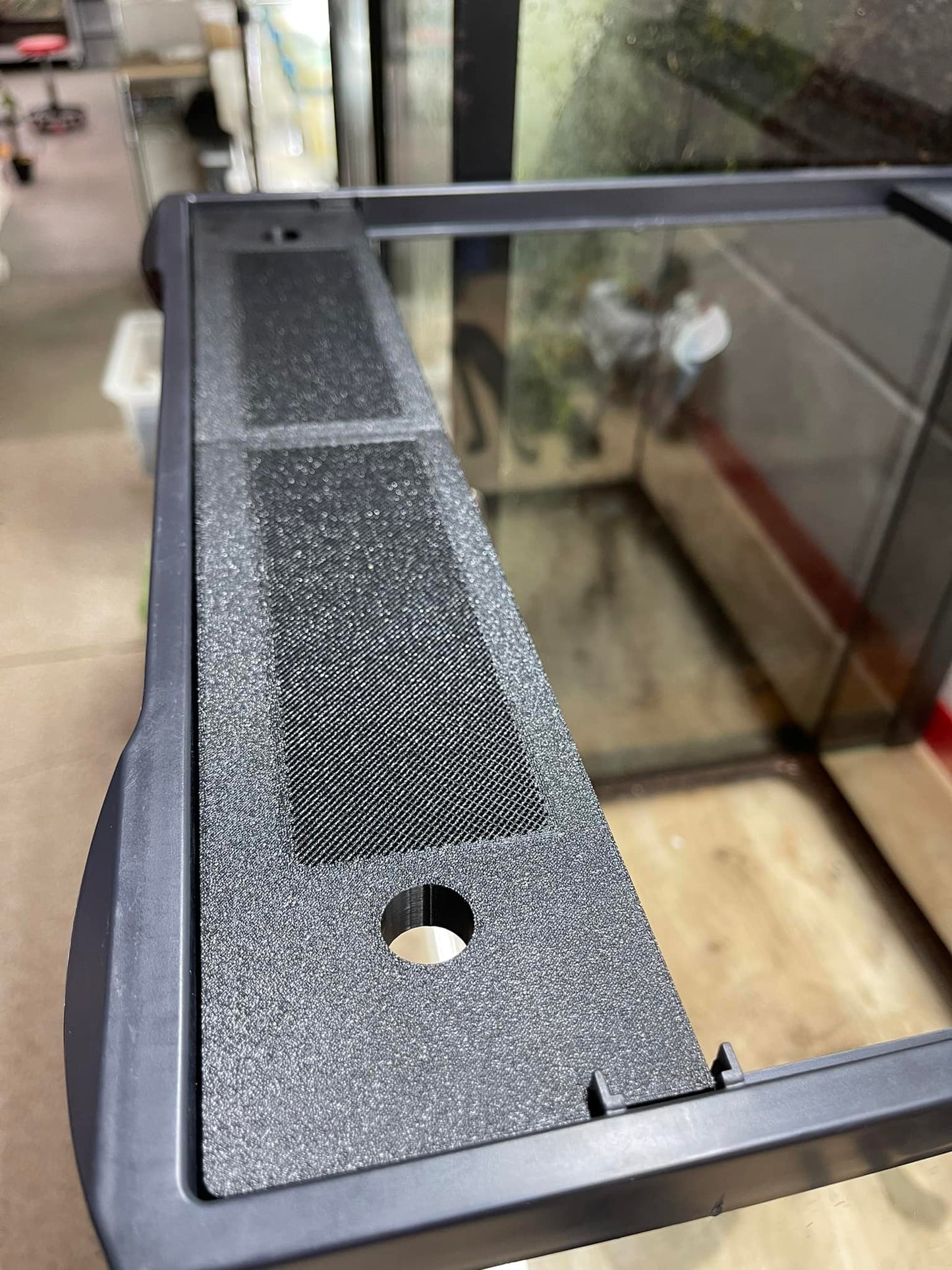 Black textured object with a circular hole on a reflective surface
