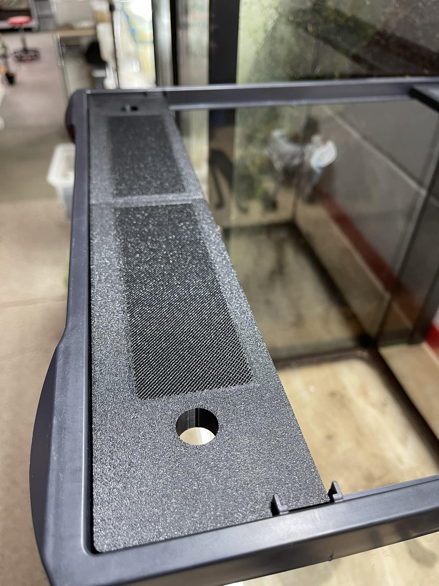 Black textured object with a circular hole on a reflective surface