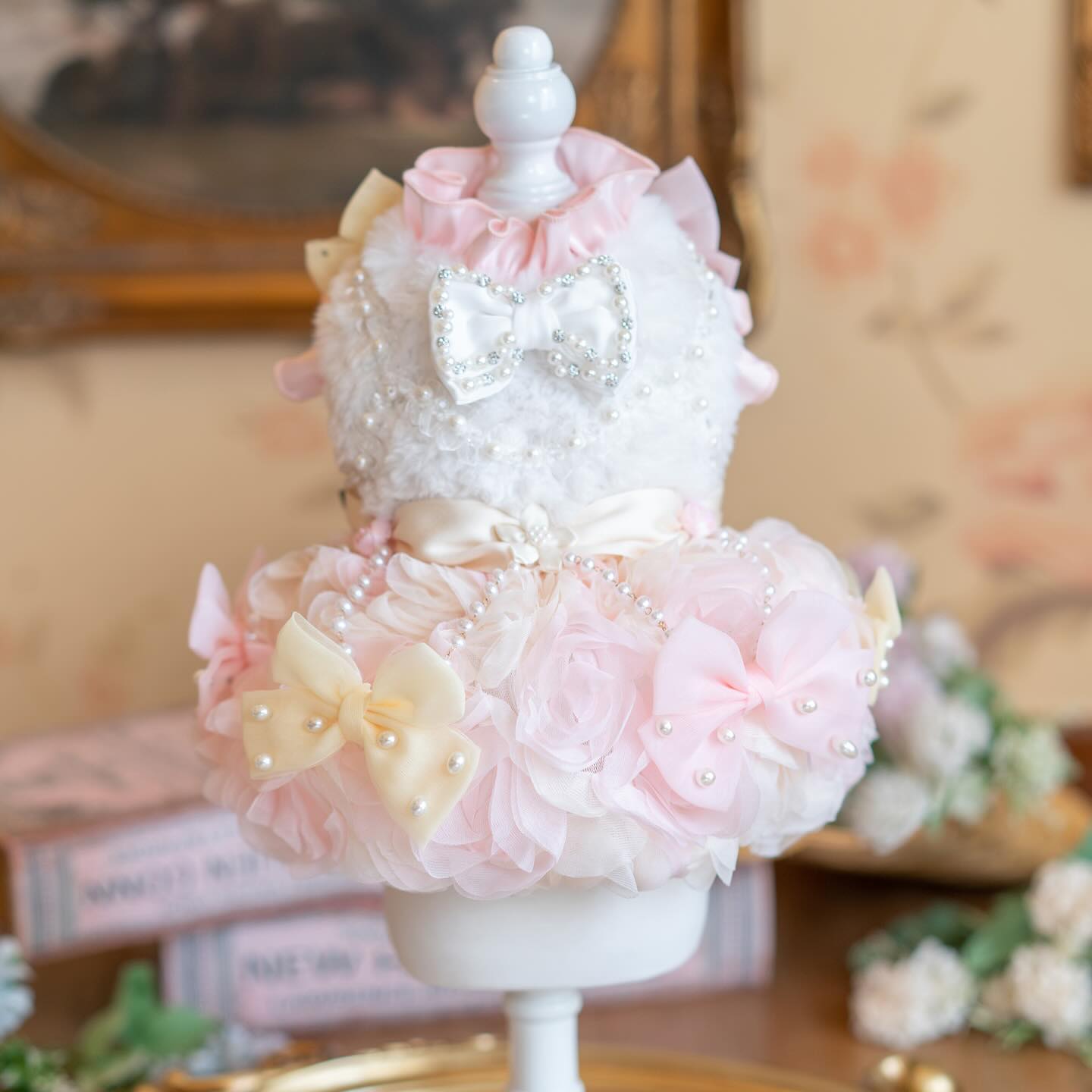 Decorative cake with pink flowers and white ribbons on a stand.