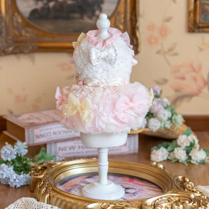 Decorative cake with pink flowers and pearls on a stand in a vintage-style room.
