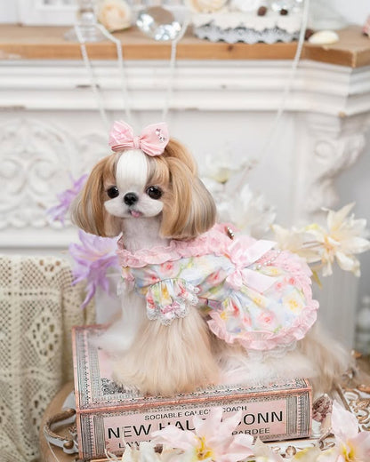 Stuffed dog toy with a floral dress and bow, sitting on a decorative box.