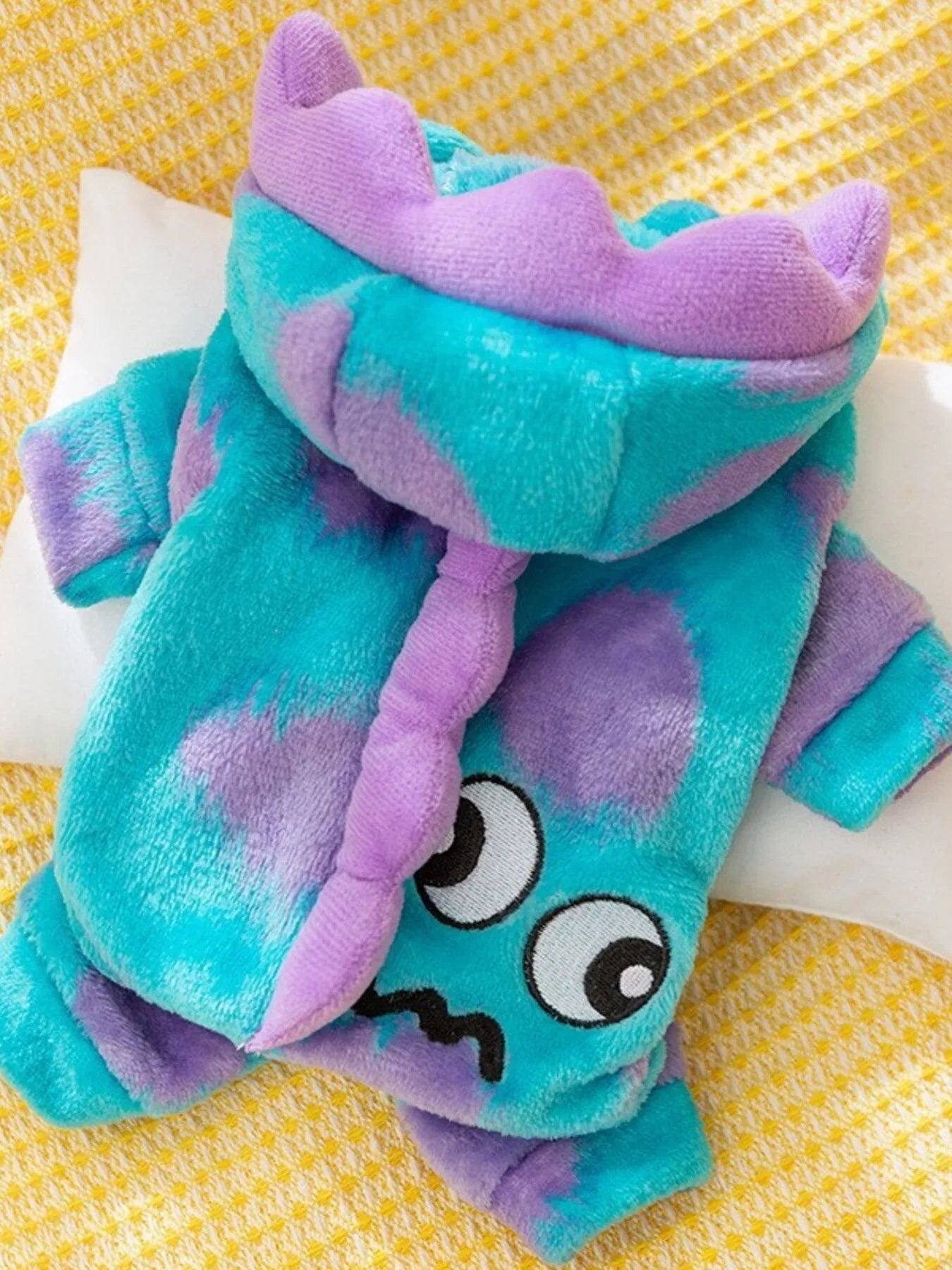 Plush toy with teal and purple colors on a yellow background