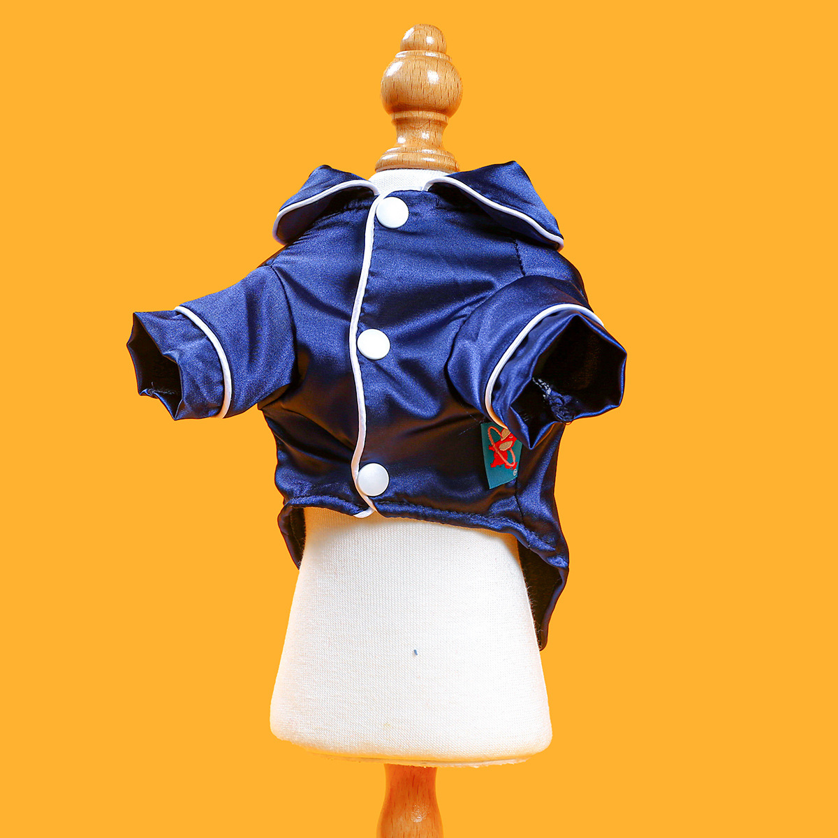 Blue jacket with white buttons on a mannequin against an orange background