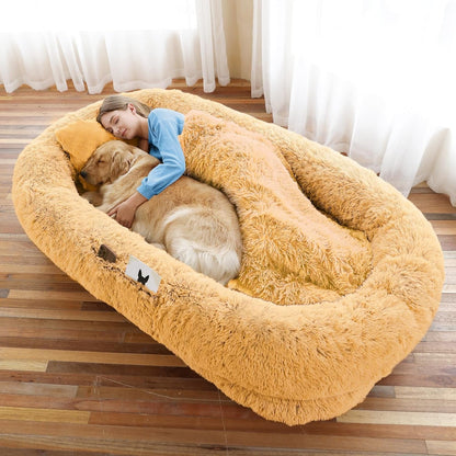 Woman and dog lying in a large, fluffy pet bed on a wooden floor.