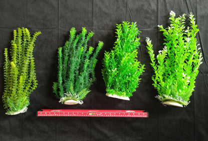 Four artificial plants of varying sizes on a black background with a ruler for scale.