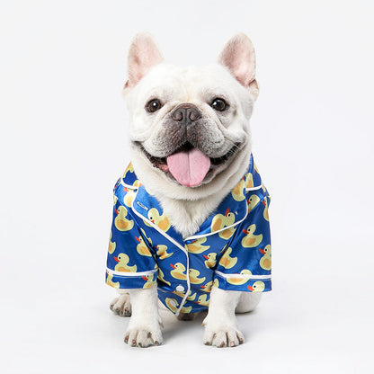 Dog wearing a blue rubber duck pajama set on a white background