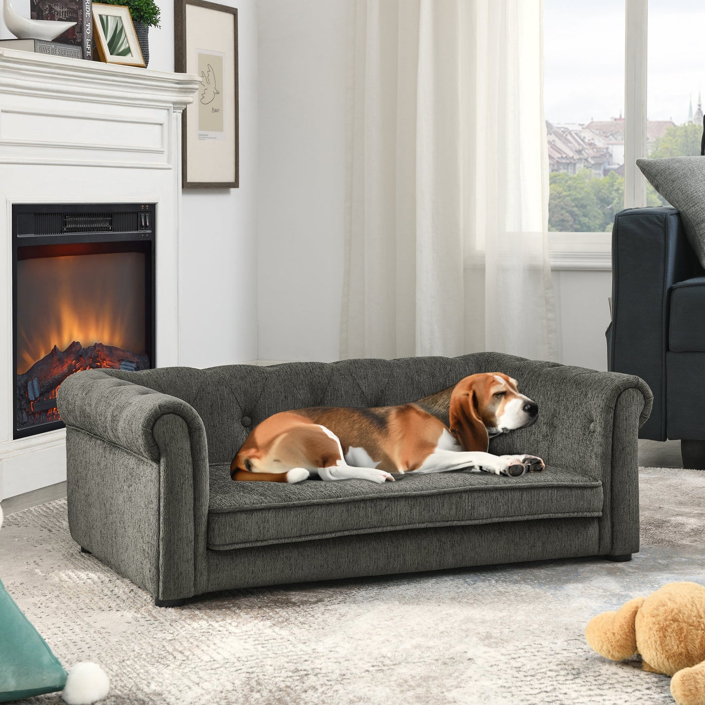 Dog lying on a gray sofa in a living room with a fireplace and window.