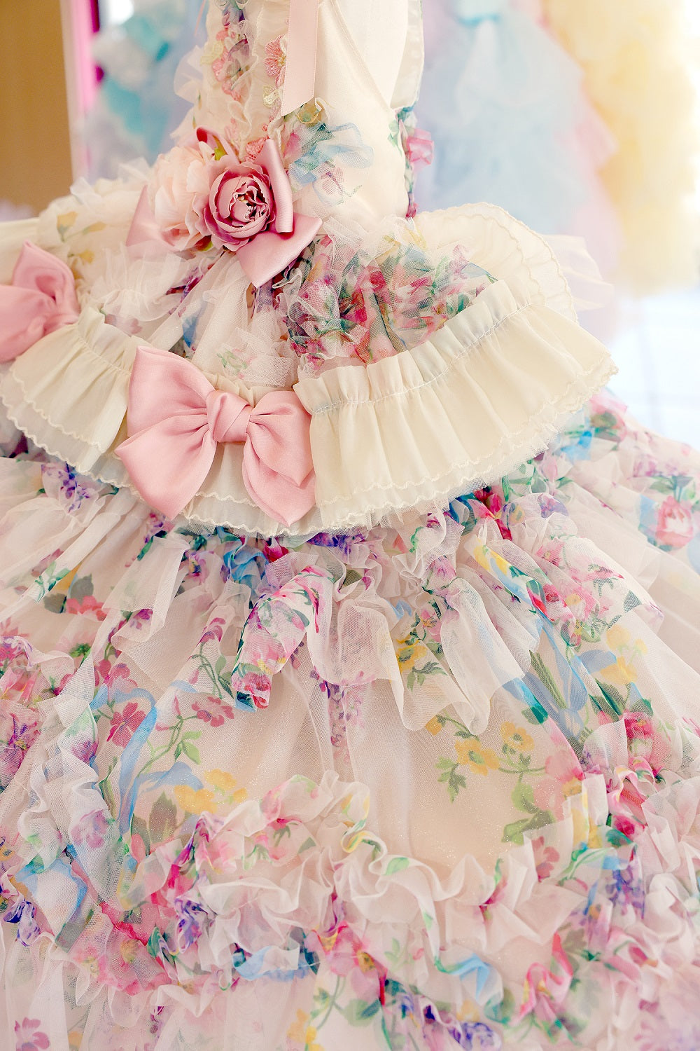 Pastel-colored floral dress with ruffles and pink bows on a blurred background