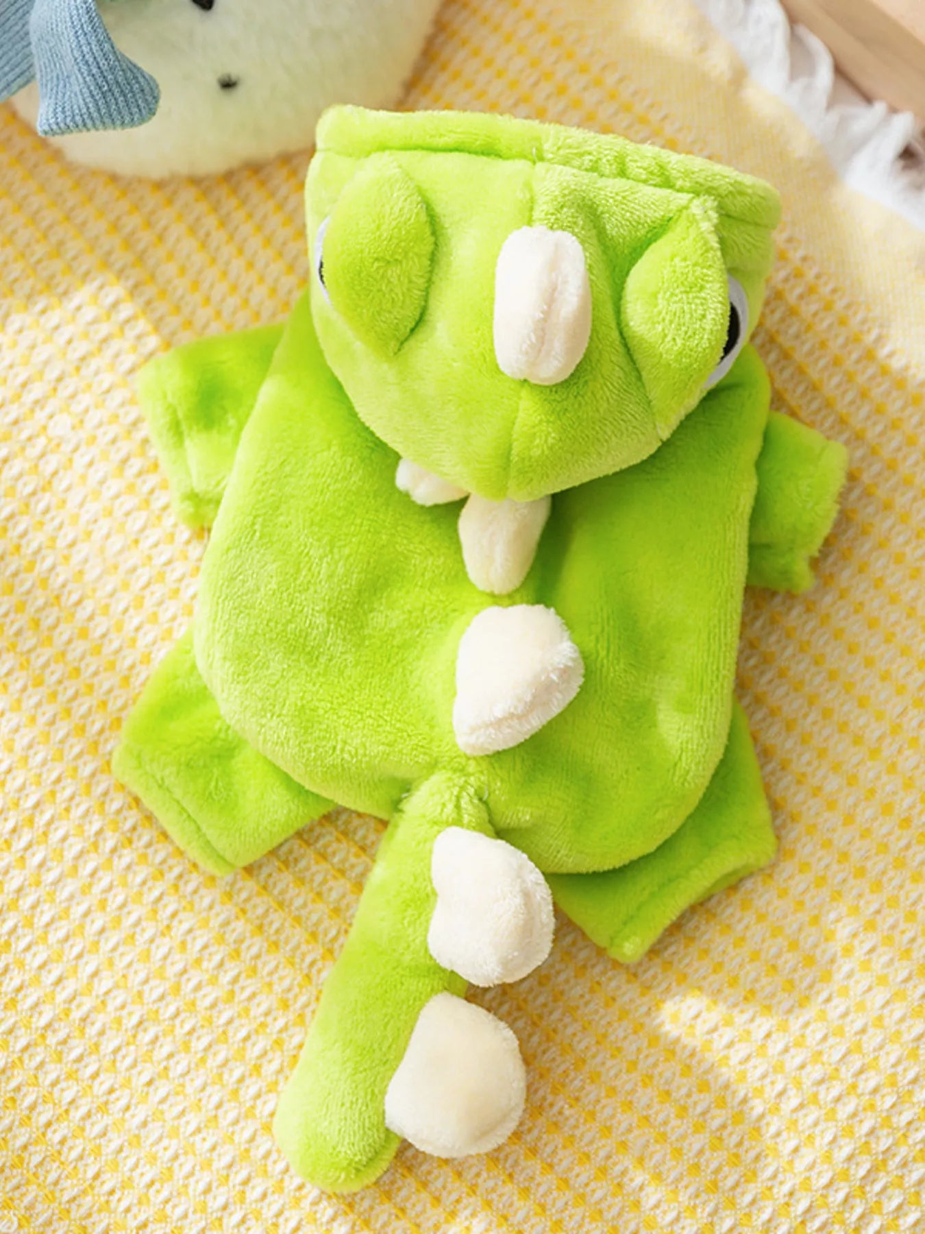 Green dinosaur-shaped plush toy on a yellow textured surface