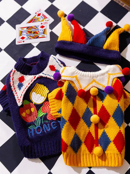 Two colorful dog sweaters on a checkered background with playing cards.