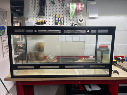 Large aquarium on a workbench with tools and equipment in the background