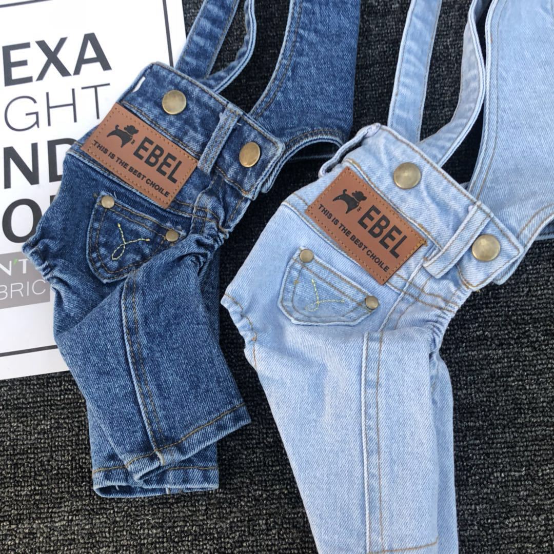 Pair of denim overalls with 'Ebel' branding on a textured surface.