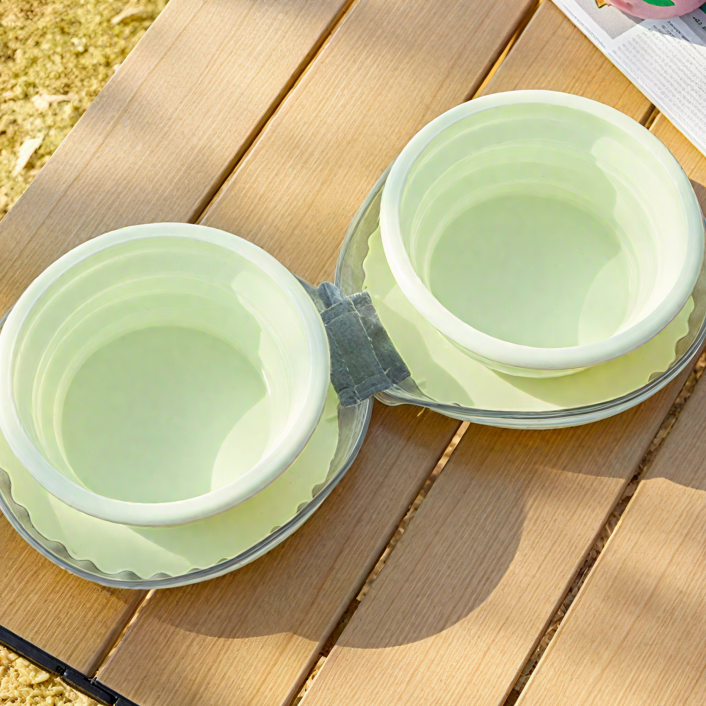 Two green collapsible bowls on a wooden surface