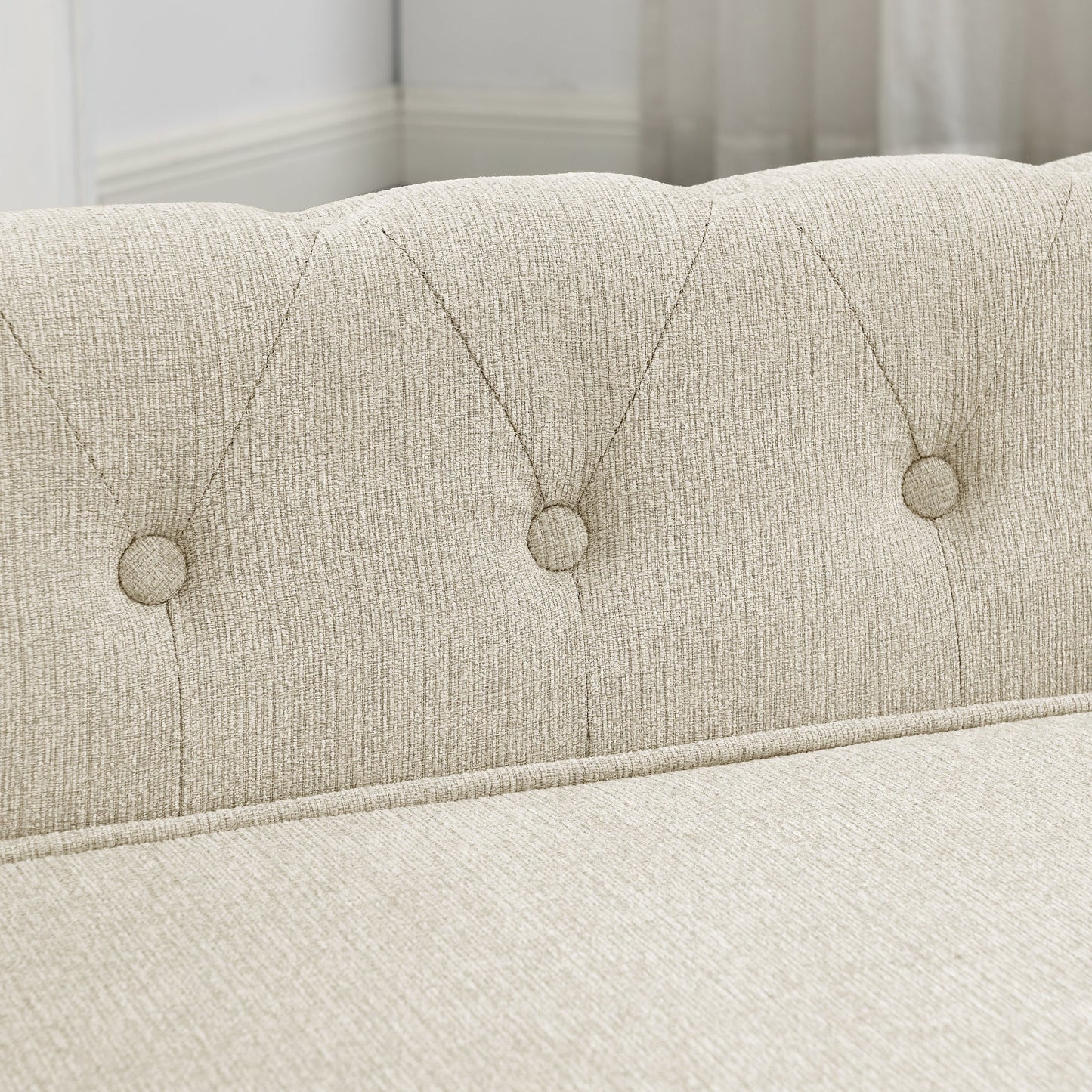 Close-up of a tufted headboard with button details on a bed.