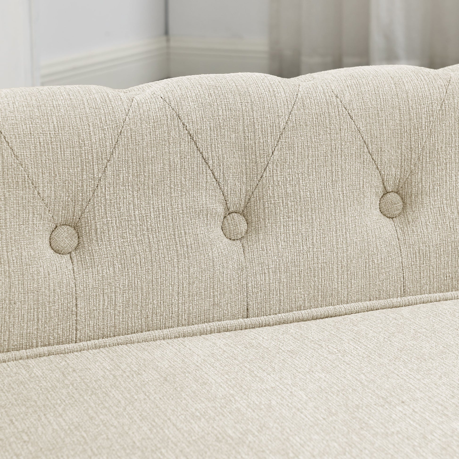 Close-up of a tufted headboard with button details on a bed.