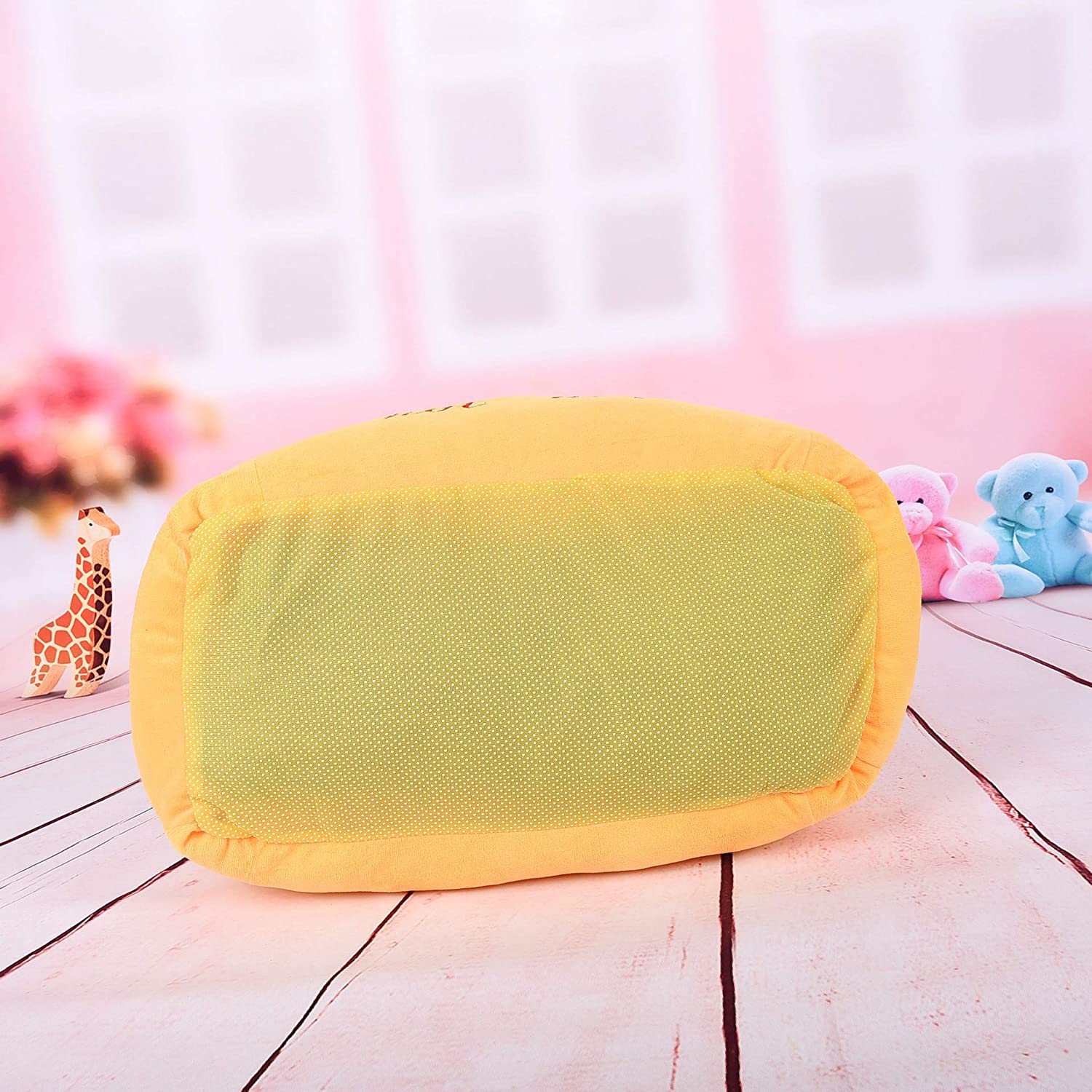 Yellow and green baby cushion on a wooden floor with toys in the background