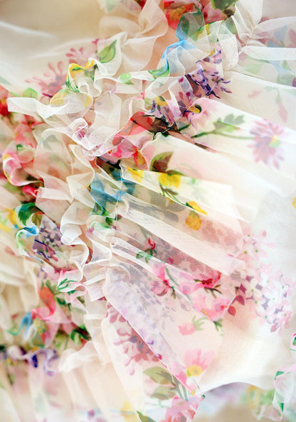 Floral dress with ruffled details in pastel colors on a white background