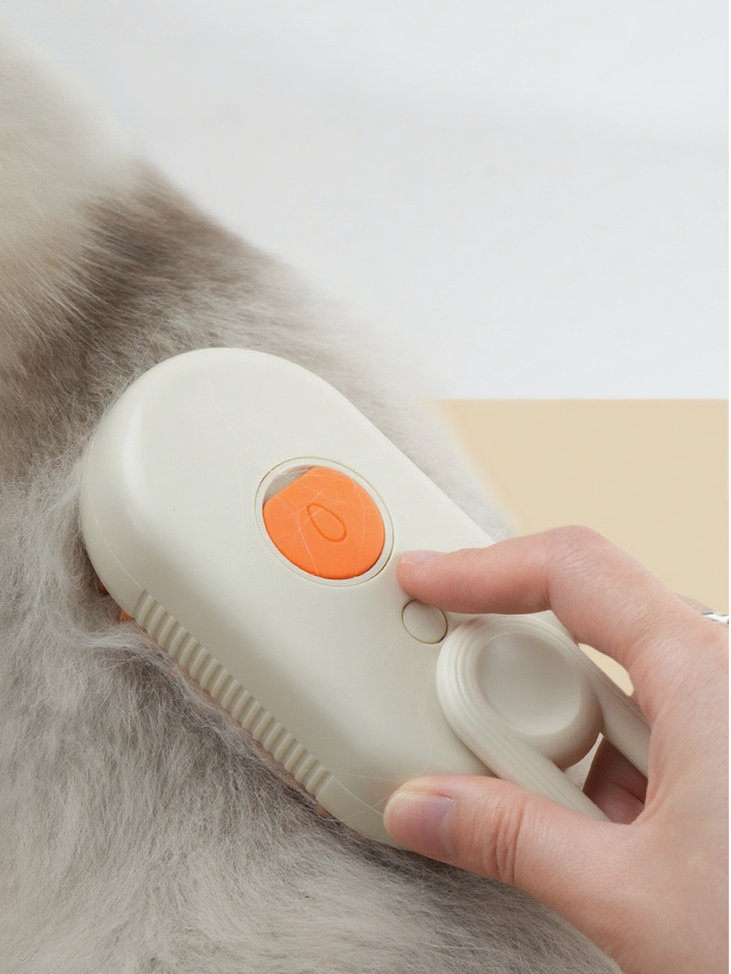 Person using a white grooming tool with an orange button on a pet's fur.