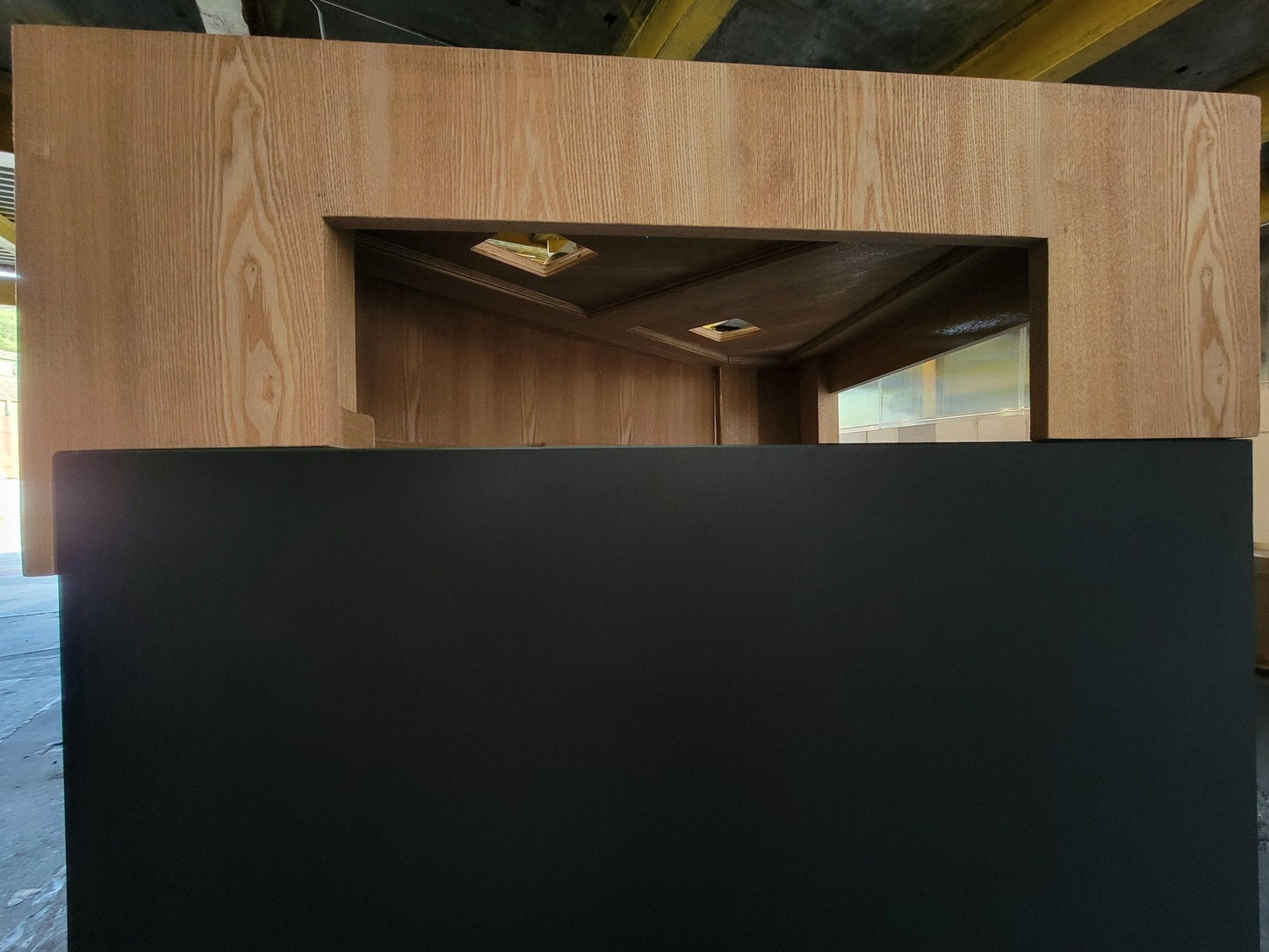 Wooden reception desk with a black front panel