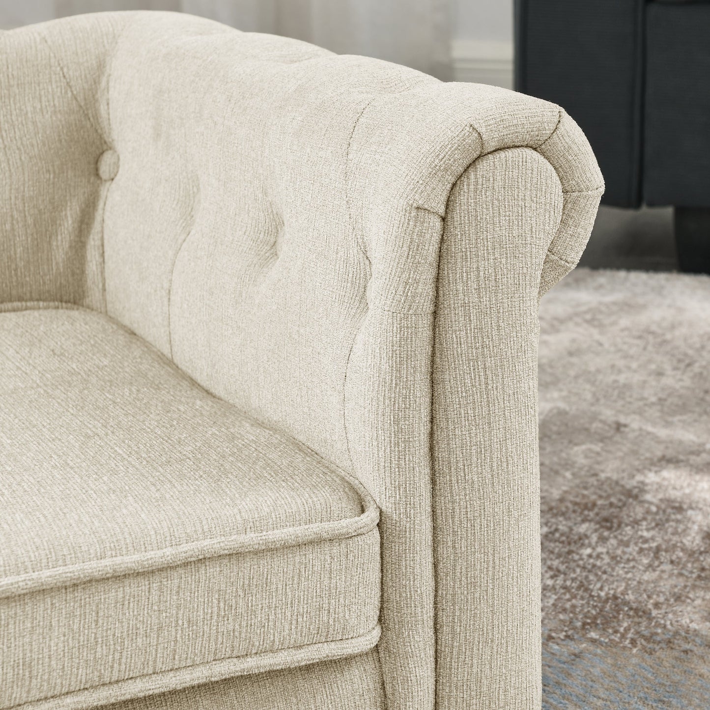 Close-up of a beige upholstered armchair with tufted detailing.