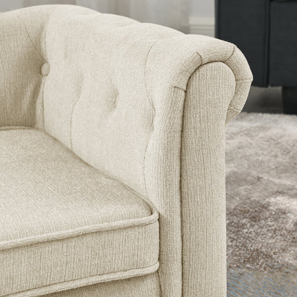 Close-up of a beige upholstered armchair with tufted detailing.