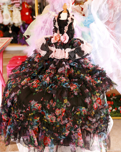 Colorful dress with floral patterns and ruffles on a mannequin against a blurred store background.
