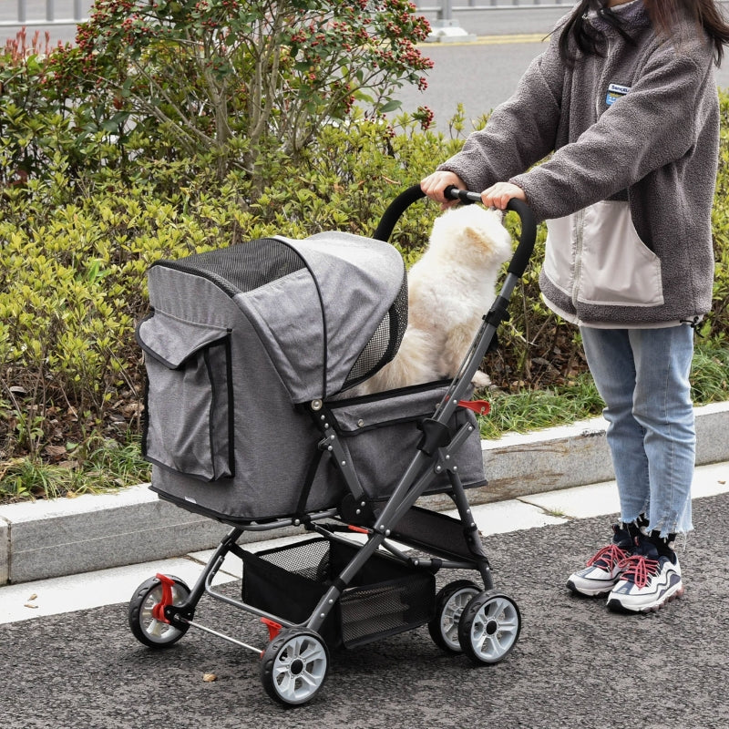 Person pushing a pet stroller with a dog inside on a sidewalk.