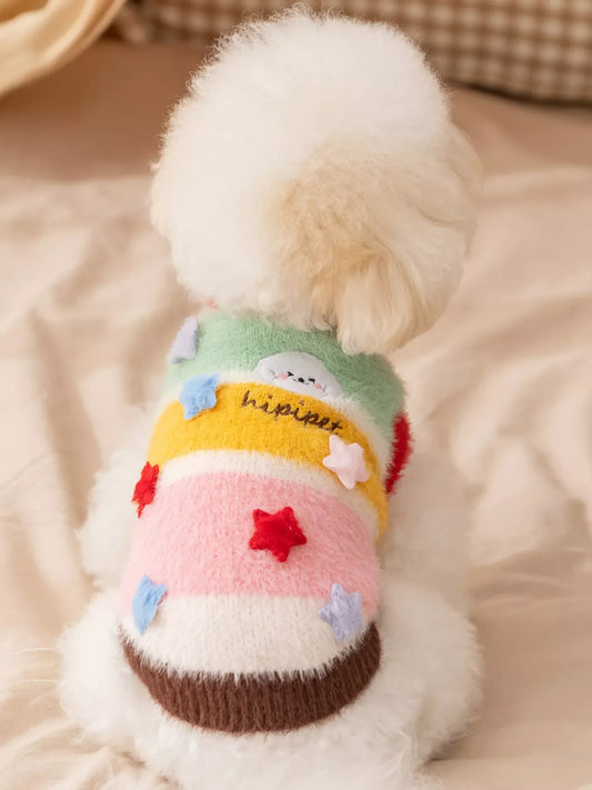 Dog wearing a colorful sweater with cartoon designs on a soft surface