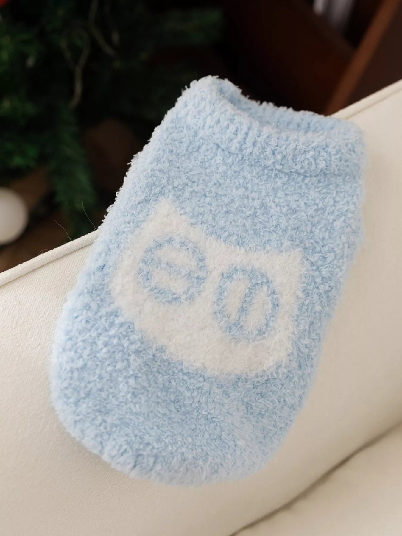 Blue fuzzy socks with a white paw print design on a beige surface.