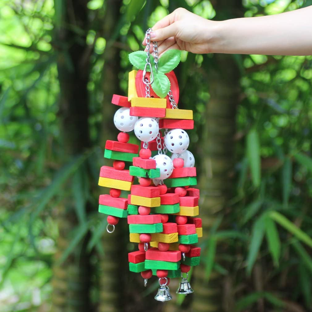 Colorful bird toy with beads and bells held by a hand against a green leafy background
