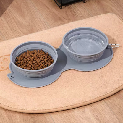 Collapsible pet bowls with food on a mat on a wooden floor