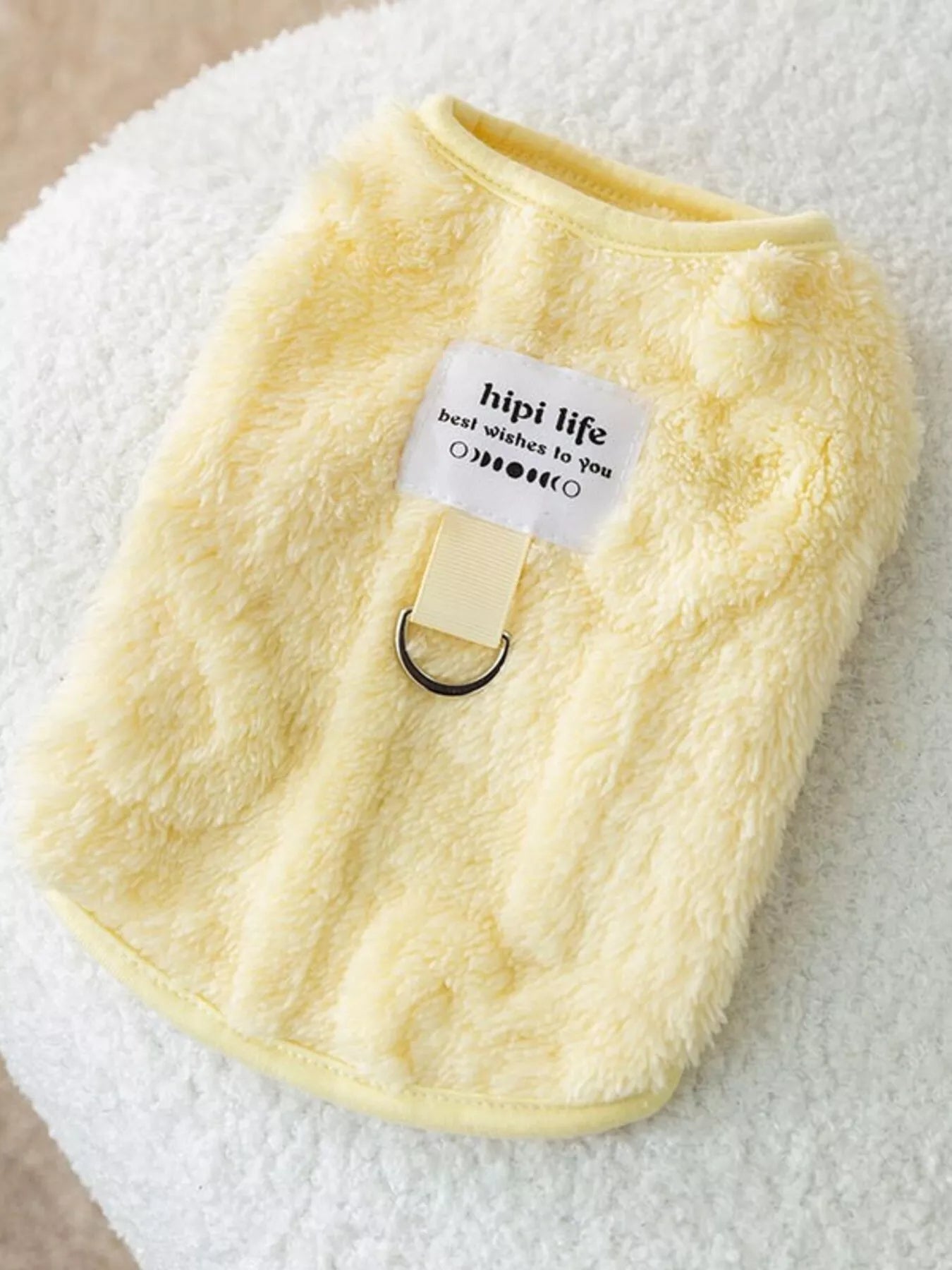 Yellow fleece pet sweater with a brand tag on a white surface